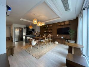 Una sala de estar con mesa y sillas y una cocina. en Misun House, en Seogwipo