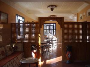 a living room with a table and chairs in a room at Au jardin de Tamnougalt in Agdz