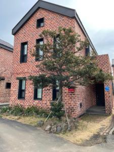 Un edificio de ladrillo con un árbol delante. en Misun House, en Seogwipo