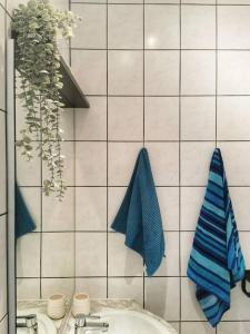 a white tiled bathroom with a sink and blue towels at Cosy apartement in Antwerp's hipster neighbourhood in Antwerp