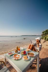 una mujer sentada en una mesa con comida en la playa en Plub Pla Koh Mak Retreat, en Ko Mak