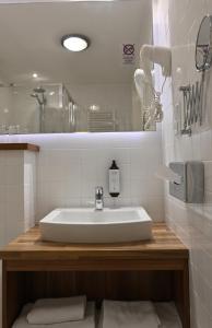 a white bathroom with a sink and a mirror at Vestil Hotel in Piotrków Trybunalski