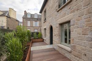 einen Holzsteg neben einem Backsteingebäude in der Unterkunft Villa l'Indépendante - Proche de la plage in Dinard