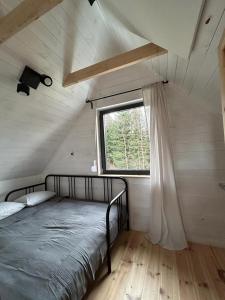 Łóżko w małym pokoju z oknem w obiekcie Sowi Sierp Domek w Górach Sowich w mieście Sierpnica