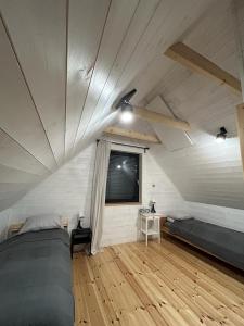 a attic bedroom with two beds and a window at Sowi Sierp Domek w Górach Sowich in Sierpnica