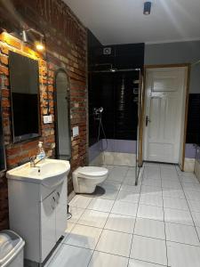 a bathroom with a white sink and a toilet at Pokoje Dworcowa 10 in Lubawa