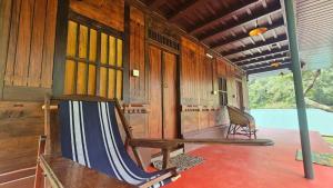a porch of a house with a hammock in it at Vattavada Jungle Resort in Munnar