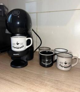 a coffee maker and four coffee cups on a counter at Le Bonheur, Limite Grenoble, Proche Tram in Seyssinet-Pariset