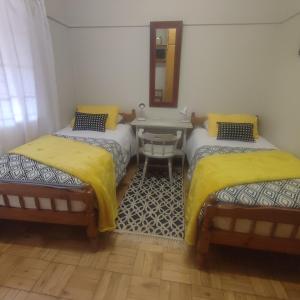 two beds in a room with a table and a mirror at Rehati Guesthouse in Potchefstroom