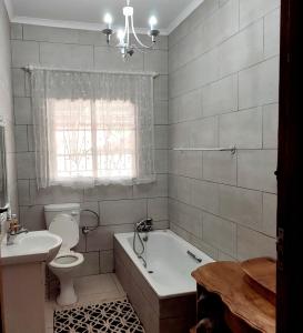 a bathroom with a tub and a toilet and a sink at Rehati Guesthouse in Potchefstroom