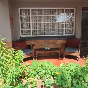 a porch with two chairs and a table in front of a window at Rehati Guesthouse in Potchefstroom