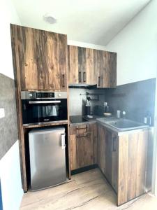 een keuken met houten kasten en roestvrijstalen apparatuur bij Magnifique Appartement Hypercentre - Le Charly in Pau