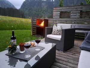 a patio with a table with wine glasses and a fire place at Appartements Moosbrugger Haus Herlinde in Schoppernau