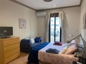 ein Schlafzimmer mit einem Bett, einem Sofa und einem TV in der Unterkunft Spatious luxe apartment Paseo de Gracia Diagonal in Barcelona