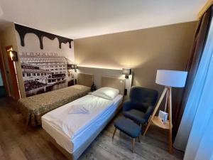 a bedroom with a bed and a chair and a lamp at Hotel & Restaurant Bergfried in Saalfeld
