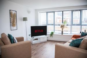 a living room with a tv and two chairs at PENTHOUSE - LIVERPOOL City Centre & Royal Hospital Location in Liverpool