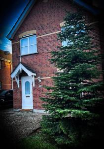 una casa de ladrillo rojo con un árbol de Navidad delante de ella en The Tree House, 