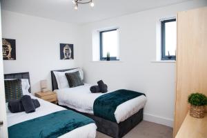 two beds in a room with white walls and windows at PENTHOUSE - LIVERPOOL City Centre & Royal Hospital Location in Liverpool