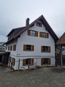 a white house with wooden windows and a gate at Ferienwohnung "Seaside Deluxe" in Lindenberg im Allgäu