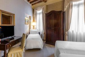 a bedroom with two beds and a desk and a television at Ca' Del Nobile in Venice