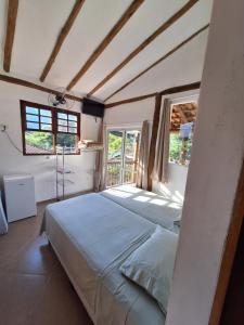 a bedroom with a bed and two windows at Alma Surf House in Boicucanga