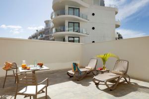 a patio with chairs and a table and a building at Marinell Collection Palm-Mar Apartments in Palm-mar