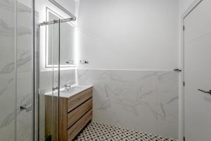 een badkamer met een wastafel en een glazen douche bij Apartamentos Pino in Benidorm