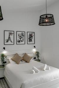 a bedroom with a white bed with pictures on the wall at Apartamentos JAP Pino in Benidorm