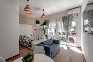een woonkamer met een blauwe bank en een slaapkamer bij Apartamentos Pino in Benidorm