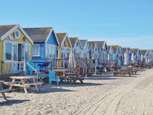 eine Reihe von Häusern am Strand mit Bänken und Tischen in der Unterkunft El Nido - Self Catering cabin in Southbourne, 5 mins from beach in Iford