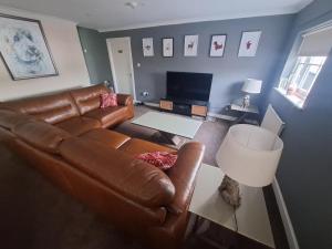 sorn inn holiday apartments في Sorn: غرفة معيشة مع أريكة جلدية وطاولة