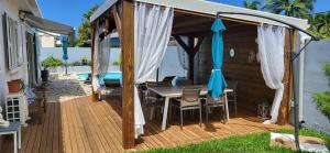 pérgola con mesa y sillas en la cubierta en VILLA THALIA à 300 m du lagon de la Saline les Bains en La Saline les Bains