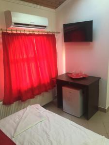 une chambre avec un rideau rouge, un lit et un bureau dans l'établissement La Pasarela, à Mamaia