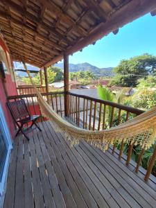 a hammock on a porch with a view of a river at Alma Surf House in Boicucanga
