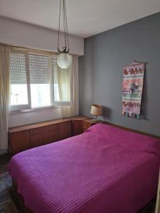 1 dormitorio con 1 cama con colcha púrpura en Departamento centro Mar del Plata en Mar del Plata