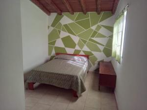 a bedroom with a bed and a green and white wall at Mi Recreo DUPLEX in Villa Cura Brochero