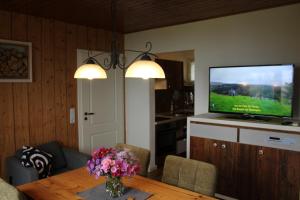 a living room with a television and a table with flowers at Ferienhaus Schau ins Land - eigene Panorama-Sauna in Schöfweg