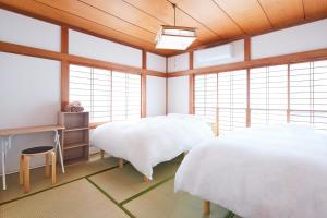 two beds in a room with wooden ceilings and windows at 世界遺産と東武日光駅に近い 全内装 3階まで階段あり 駐車場 子供不可 in Nikko
