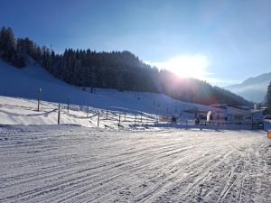 una pista de esquí cubierta de nieve con el sol en el fondo en Ferienwohnung Alpenglück hoch3, en Oy-Mittelberg