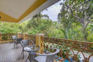 a balcony with chairs and tables and trees at Tropical villa by Happyinch in Saligao