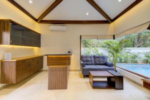 uma cozinha e sala de estar com um sofá e uma piscina em Tropical villa by Happyinch em Saligao