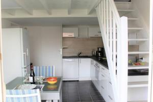 a small kitchen with white cabinets and a table at Belles prestations pour ce pavillon moderne avec piscine - 6CYC59 in Saint-Cyprien-Plage