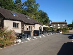 a building with benches and tables on the side of the road at Lile Cottage at Gleaston Water Mill in Ulverston