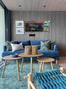 a living room with a blue couch and two tables at Waterfront apartment with panoramic sea view in Henningsvær