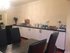 a kitchen with white cabinets and a counter top at London Heathrow Guesthouse in Hillingdon