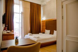 a bedroom with a bed and a table and a window at Solo Hotel in Baku