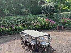 una mesa de madera con sillas y flores en un jardín en *Bellevue* Demeure vue Cher et Château, en Seigy