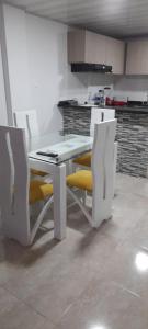 a kitchen with a white table and yellow chairs at Apartamento ideal para descansar in San Gil