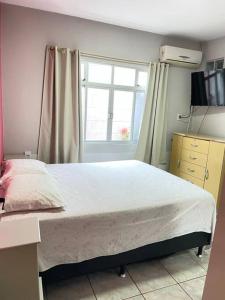 um quarto com uma cama grande e uma janela em Residência Gramal do Campeche em Florianópolis