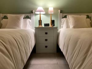 2 camas con sábanas blancas y mesita de noche con lámpara en Fondamaria - Alojamiento rural en Lesaka
